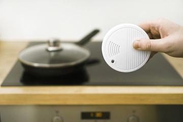Man holding smoke detector in the kitchen.