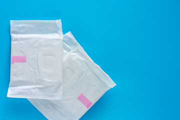 Feminine sanitary napkin, an absorbent item worn by a woman while menstruating, on blue background for hygiene and health concept