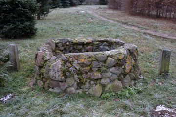 Old hidden manhole from the cobblestones among the grass and dry fallen leaves