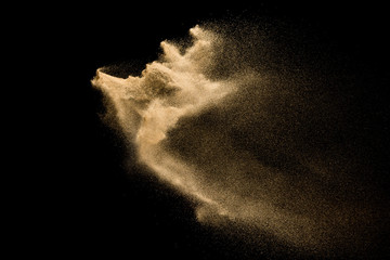 Dry river sand explosion. Golden color sand splash against  black background.