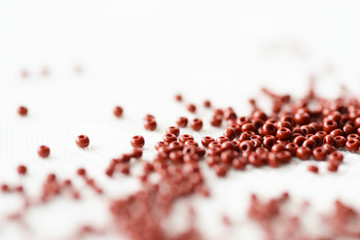 Brown seed beads scattered on textile background close up