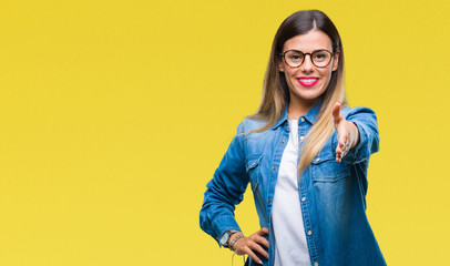 Young beautiful woman over wearing glasses over isolated background smiling friendly offering handshake as greeting and welcoming. Successful business.