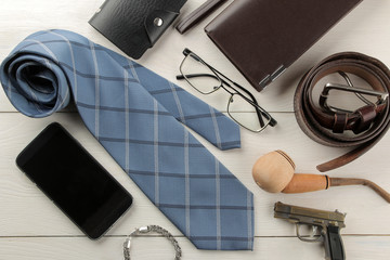 Men's Accessories. men's style. Tie, belt, glasses, smoking pipe, wallet on a white wooden background. flat lay.