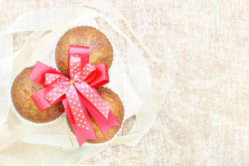 Close up group of banana cup cake bakery on wood plate top view with ribbon and red big bow look delicious on wooden table background, vintage tone, have copy space.