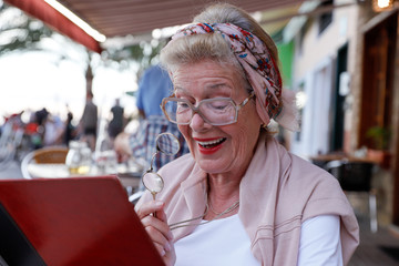 Attractive 78 year old woman during a summer restaurant visit. Authentic, natural, unplugged.