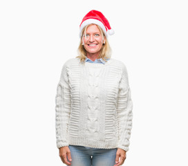 Middle age blonde woman wearing christmas hat over isolated background with a happy and cool smile on face. Lucky person.