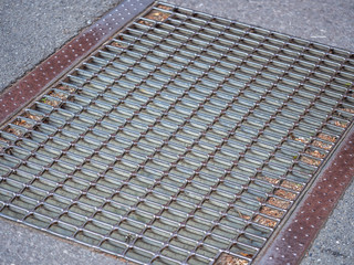 Abstract and closeup of grids pattern of metal cover water drain on cement or concrete street floor.