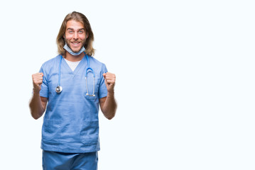 Young handsome doctor man with long hair over isolated background celebrating surprised and amazed for success with arms raised and open eyes. Winner concept.