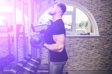 Fototapeta na wymiar Blonde man is training in the gym with weights. Handsome guy is doing exercises for good muscles. Fitness personal trainer is at work. Sport motivation healthy lifestyle. Fit bodybuilder.
