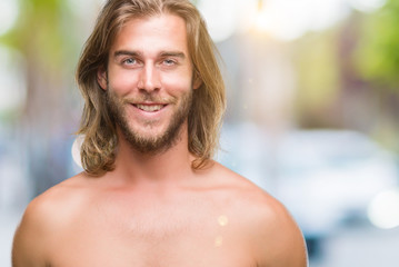 Young handsome shirtless man with long hair showing sexy body over isolated background with a happy and cool smile on face. Lucky person.