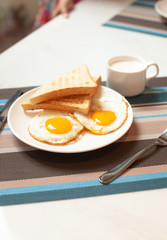 Two fried eggs on a plate with toast for Breakfast