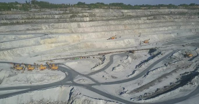 numerous excavators stand on pit terraces crossed by tracks