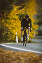 Professional road bicycle racer in action. Men cycling mountain road bike at sunset.