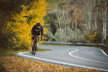 Professional road bicycle racer in action. Men cycling mountain road bike at sunset.