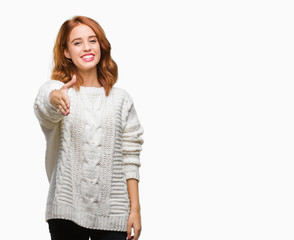 Young beautiful woman over isolated background wearing winter sweater smiling friendly offering handshake as greeting and welcoming. Successful business.