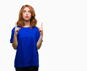 Young beautiful woman over isolated background amazed and surprised looking up and pointing with fingers and raised arms.