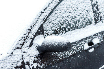 Car covered after snowfall. View of a side mirror machine