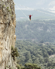 Obraz premium Highliner on a rope. Highline on a background of mountains. Extreme sport on the nature. Balancing on the sling. Equilibrium at altitude.