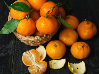 Juicy bright ripe tangerines in wooden basket on dark background