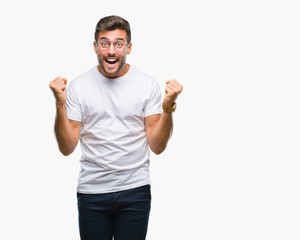 Young handsome man wearing glasses over isolated background celebrating surprised and amazed for success with arms raised and open eyes. Winner concept.