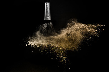 gold powder splash and brush for makeup artist or graphic design in black background, look like a luxury mood