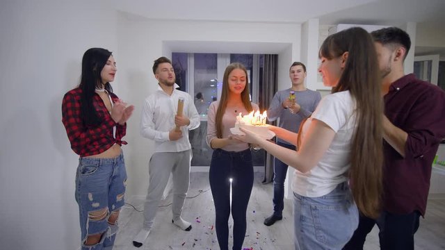 happy birthday, group of funny friends of boys and girls congratulate girlfriend on holiday which blows out candles on cake and clap flappers and serpentine at home at holiday