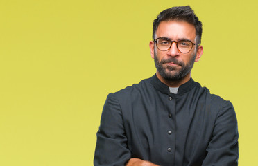 Adult hispanic catholic priest man over isolated background skeptic and nervous, disapproving...