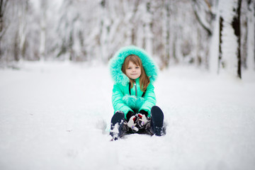 Fototapeta na wymiar Funny little girl having fun in beautiful park during snowfall