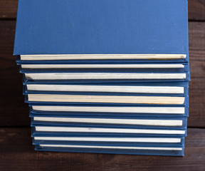 large stack of books in a blue cover on a brown wooden table
