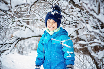 boy in snow in Park. boy plays in winter wood. Adorable child having fun in winter park. playing outdoors with snow.