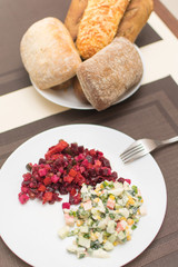 Two different salad vinaigrette and Olivier on a white plate.