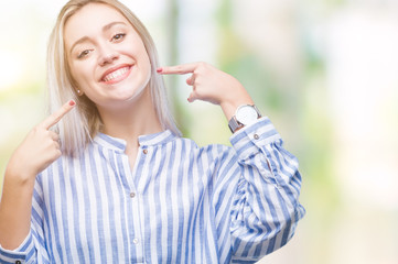 Young blonde woman over isolated background smiling confident showing and pointing with fingers teeth and mouth. Health concept.