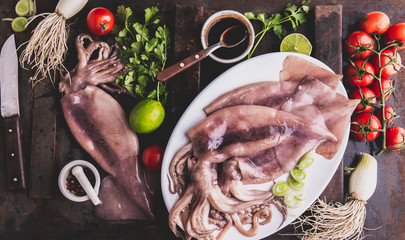 Raw squid calamary on white plate with ingredients for cooking korean BBQ squid. Top view - obrazy, fototapety, plakaty