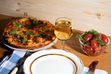 A plate with pizza, a glass of white wine, canned tomatoes on a napkin.