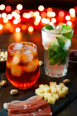 Happy hour with aperol spritz, mojito, prosciutto, olives, pistachios and cheese. Festive lights in...