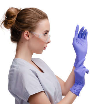 Beautiful female doctor or nurse wearing protective glasses, putting on latex or rubber gloves on white background isolated. Health care concept