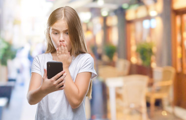 Young beautiful girl sending message texting using smarpthone over isolated background cover mouth with hand shocked with shame for mistake, expression of fear, scared in silence, secret concept