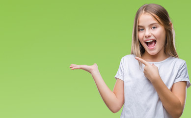 Young beautiful girl over isolated background amazed and smiling to the camera while presenting with hand and pointing with finger.