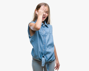 Young beautiful girl over isolated background covering one eye with hand with confident smile on face and surprise emotion.