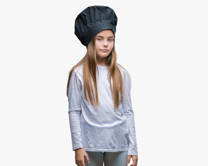 Young beautiful girl wearing chef hat uniform over isolated background with serious expression on face. Simple and natural looking at the camera.