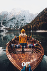 Beautiful young girl in hat sitting on a boat in autumn at beautiful famous place at Lago Di Braies,Italy