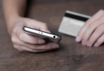 Close-up woman's hands holding a credit card and using smartphone for online shopping