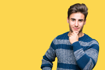 Young handsome man over isolated background looking confident at the camera with smile with crossed arms and hand raised on chin. Thinking positive.