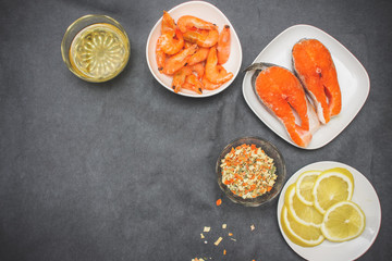 On gray paper 5 plates first shrimp raw Dahlia salmon sliced lemon slices pepper seasoning.