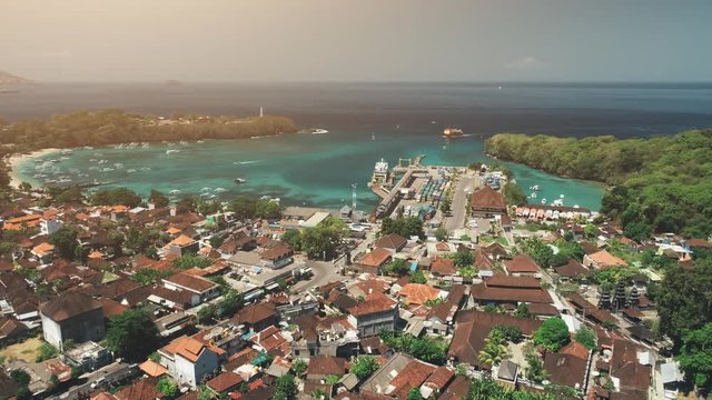 Drone Flight over jungle village. Ocean bay, houses, Harbor, Port, Pier in sunset light. Travel Tourism Concept. Beautiful nature landscape. Tropical Bali Island, Indonesia. Cinematic Fast Speed 4K