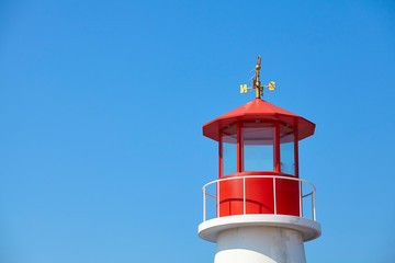 Red top of a lighthouse against the blue sky.
