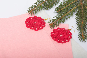 Knitted earrings on the background of felt fabric. Near spruce branch.