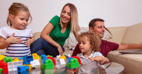Family time – Smiling children with man and woman playing with blocks toys.