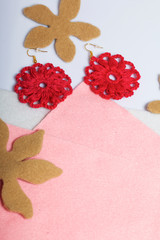 Knitted earrings on the background of felt fabric. Near spruce branch.