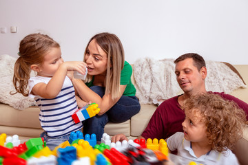 Smiling man and woman playing with children at home..